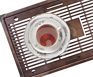 Antique cup with tea and a fine porcelain saucer, on a Chinese tea board