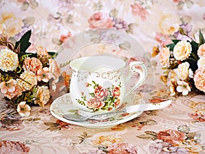 Antique cup of tea with saucer ,yellow orange rose flowers background ,porcelain vintage style ,old English coffee cup still life