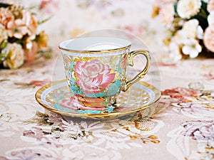 Antique cup of tea with saucer ,yellow orange rose flowers background ,porcelain vintage style ,old English coffee cup still life