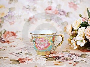 Antique cup of tea with saucer ,yellow orange rose flowers background ,porcelain vintage style ,old English coffee cup still life