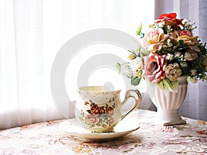 Antique cup of tea with yellow orange rose flowers background porcelain teacup vintage style