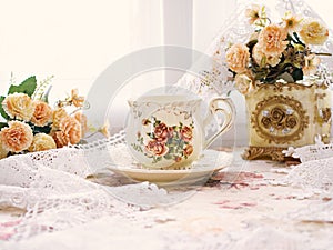 Antique cup of tea with yellow orange rose flowers background ,porcelain teacup vintage style ,old English coffee cup