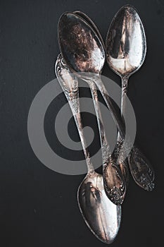 Antique cutlery on black background. Silver spoons isolated. Silverware with copy space. Silver cutlery. Stylish retro utensil.