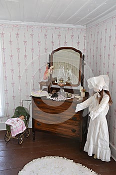 Antique doll carriage and mannequin in an old fashioned bedroom