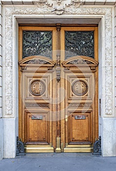 Antique double door entrance of old building in Paris France. Vintage wooden doorway and stucco fretwork wall.