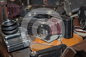 Antique Folding Camera with Bellows in a Pile of Old Cameras