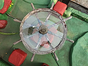 Antique glass table with old wooden frame model of a ship& x27;s rudder located in the garden
