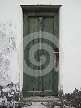 Antique green wooden door on the white old wall