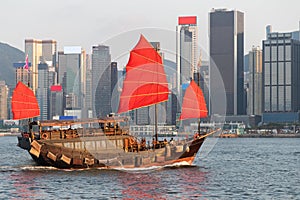 Antique junk boat with tourists in Victoria Harbour, Hong Kong, skyline of buildings in background