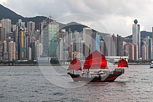 Antique junk boat with tourists in Victoria Harbour, Hong Kong, skyline of buildings in background