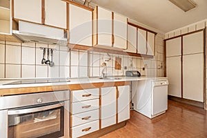 Antique kitchen with edge wood cabinets, chests of drawers and cabinets, light brown flooring and cream tile on the walls