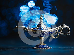 Antique lamp. Fairy lamp of Aladdin granting wishes on a blue background. Antique item adorned with precious stones. There are no