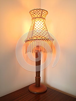 Antique lampshade tassels wooden vintage lamp on wooden bedside table.