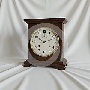 Antique mantel clock with a rectangular dark wood case. The clock face is circular,