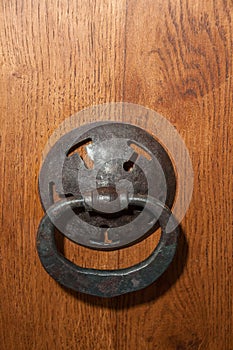Antique metal handle in form of ring on wooden door