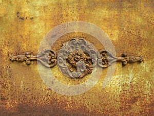 Antique metal ornamental detail on rusty yellow wrought iron wall. Rusty painted old ornate decorative wrought metal grill in