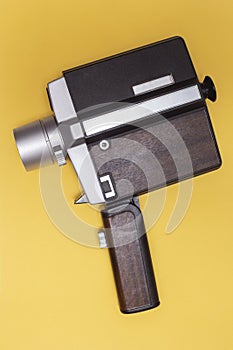 Antique movie camera. analog filming. zenithal view on vintage pastel yellow background