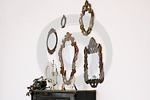 Antique old mirrors on a white wall indoor. Interior design