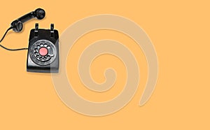 Antique old rotary dial telephone on orange background