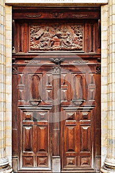 Antique and ornate wooden double door of an old church with religious relief