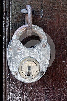 antique padlock hung on closed wooden door photo