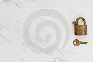 An antique padlock and key on a white marble countertop with neg