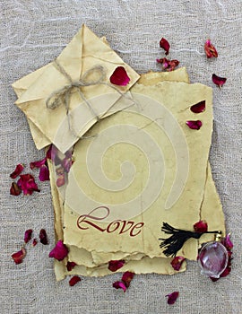 Antique parchment paper love letters with rose petals and perfume bottle