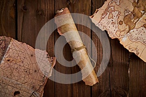 Antique parchment scroll with old maps on a wooden table.