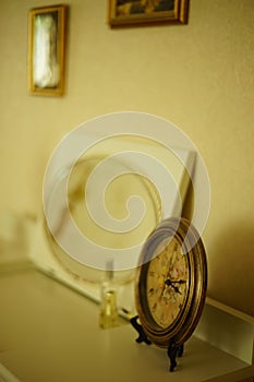 Antique Paris clock on a white vanity table with an oval mirror and paintings on the wall