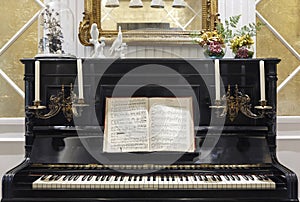 Antique piano with candles and musical score. Indoor decoration.