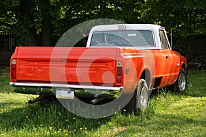 The antique pick-up truck is orange.