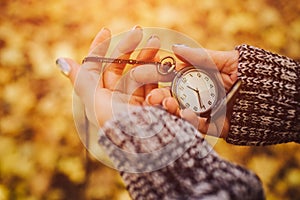 Antique pocket clock in hands on an autumn background close-up on the street