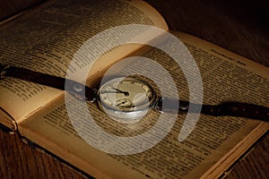 Antique pocket watch and ancient open book. Retro style objects. Vintage silver clock with chain on book. Nostalgia concept.