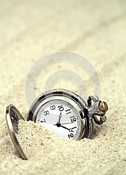 Antique pocket watch buried in sand