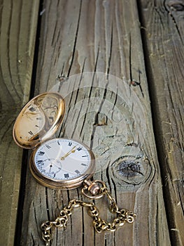 Antique pocket watch and fob chain on aged wooden boards