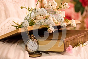 Antique pocket watch, opened books, flowers