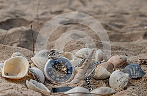 Antique pocket watch and shells in sand on the beach