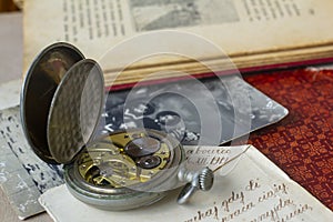 Antique pocket watch with Victorian items. Old books and photographs. Pocket watch mechanism close-up