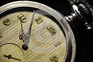 Antique pocket watch with vintage golden arrows on the old yellowed dial and clockwork key on a dark background. Time, history, te