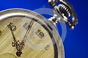 Antique pocket watch with vintage golden arrows on the old yellowed dial and clockwork key on a dark background. Time, history, te