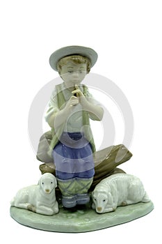 Antique porcelain figure of a boy shepherd playing the whistle or pipes sitting on a log with two sheep or lambs at his feet