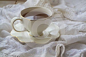 Antique porcelain tea cup full of tea on white vintage background