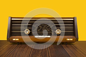 Antique radio on a yellow background with dark brown wooden