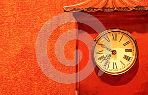 Antique red clock timepiece on a red wallpaper