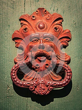 Antique red door knocker of an old door in Italy.