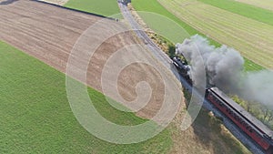 Antique restored steam locomotive pulling passenger cars traveling thru the countryside blowing black smoke and