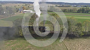 Antique restored steam locomotive traveling in the countryside blowing black smoke and steam thru the