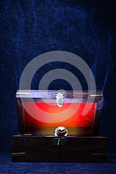 Antique retro wooden box ajar with a jewellry ring and a red light inside it on a dark background
