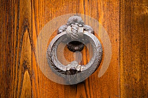 Antique round metal handle on a wooden front door. Beautiful brown color elegant entrance handle on the door. Vintage