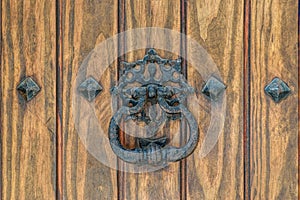 An antique rusted door handle on a weathered wooden door